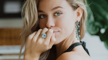 female model with hand on chin, blue gemstone ring on finger