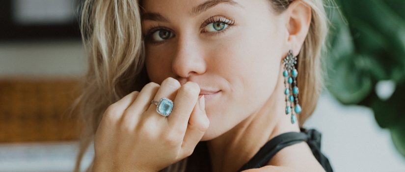 female model with hand on chin, blue gemstone ring on finger