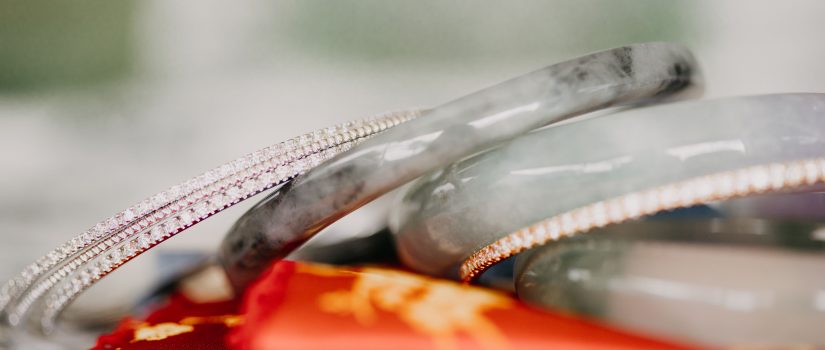 stack of mixed jadeite and diamond bracelets atop a scarlet cloth