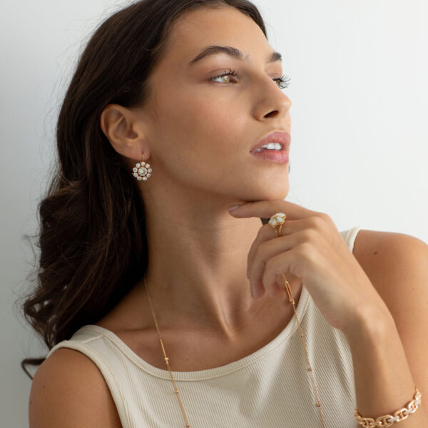 Brunette woman holding her chin gently while wearing stunning earrings, rings, and a necklace